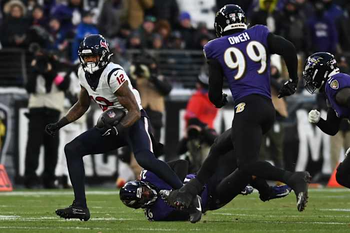 Texans wide receiver Nico Collins runs the ball against Baltimore Ravens safety Geno Stone and linebacker Odafe Oweh during the first quarter of a 2024 AFC divisional round game at M&T Bank Stadium.